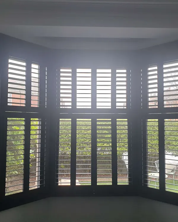 Grey Boston range shutters fitted across a bay window in a living room