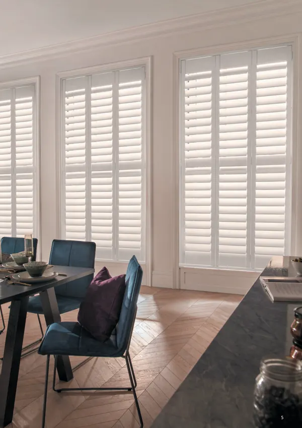 Dining room with a wooden floor and full-height white shutters