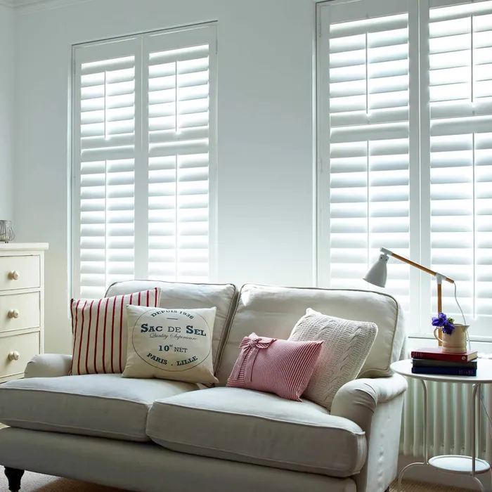 Bright living room with two tall windows behind full-height white shutters