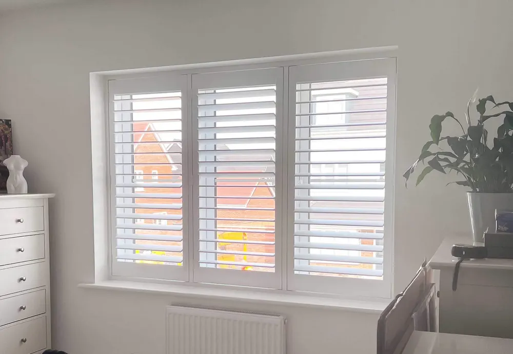 Living room with a run of windows, each fitted with white full height shutters