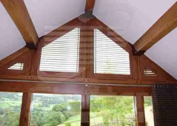 Gable window with hardwood shutters made to its shape in an oak finish