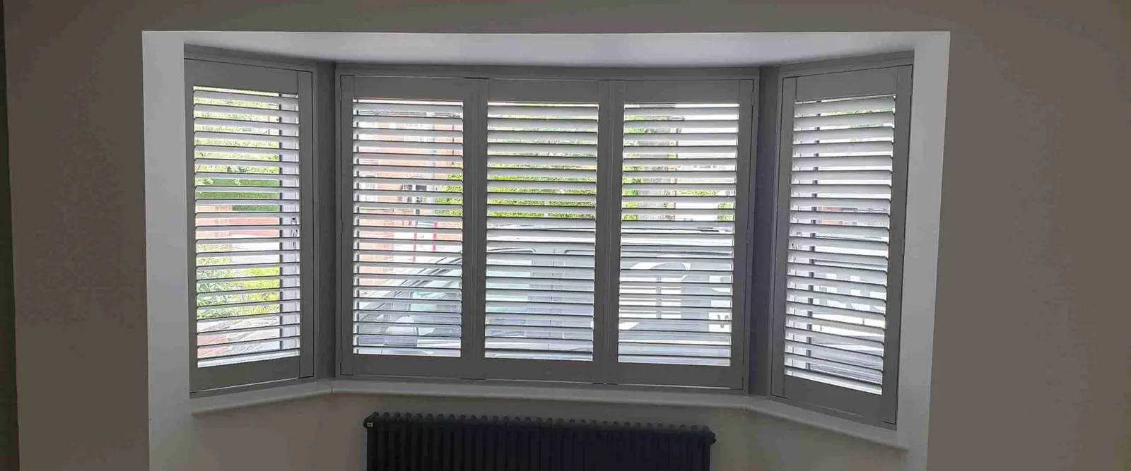 Lounge with an angled bay window covered by white shutters on each face