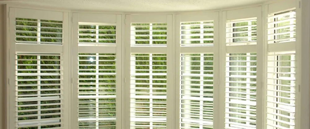 Wide bay window lined with white shutters, with a row of smaller panels across the top
