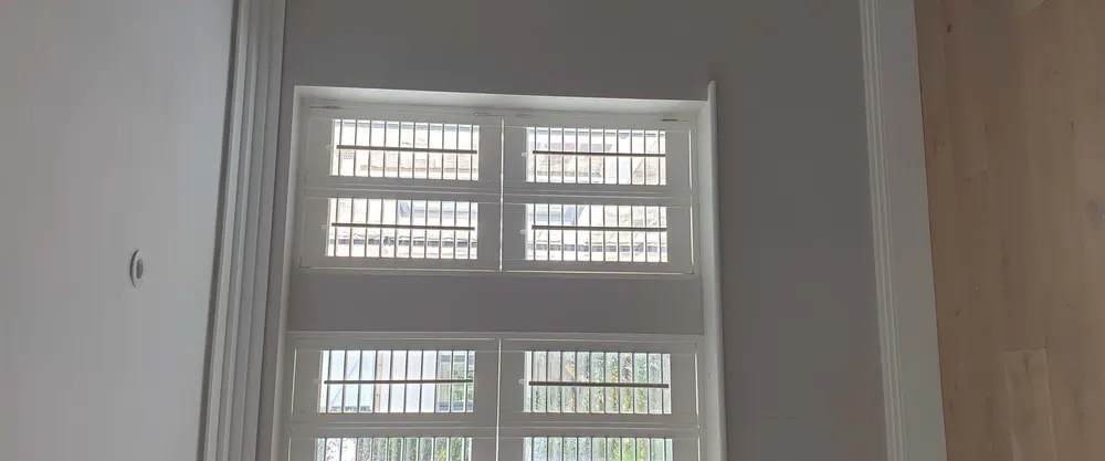 Tall window with white shutters split into three rows of louvred panels