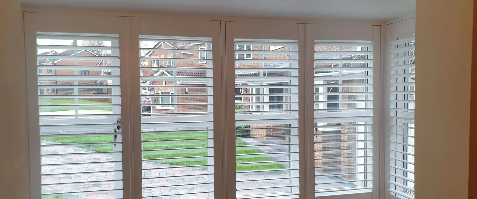 White shutters fitted on each face of a square bay