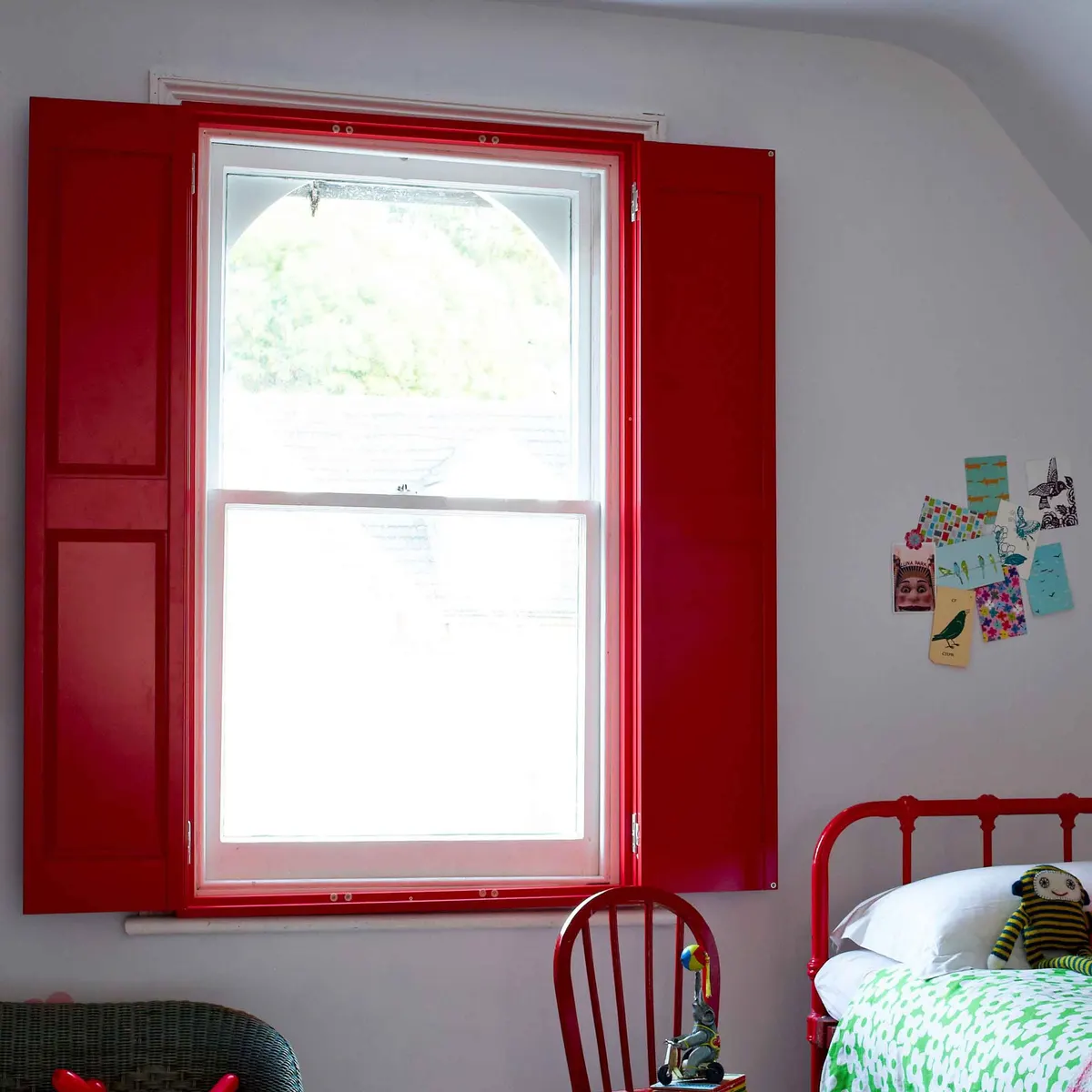 Child's bedroom sash window with red painted solid panel shutters