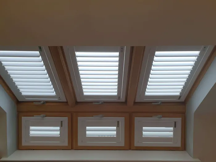 A loft ceiling with a run of white skylight shutters