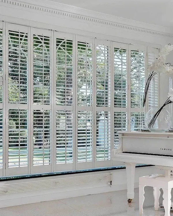 Seattle range white shutters in a bright conservatory beside a white grand piano