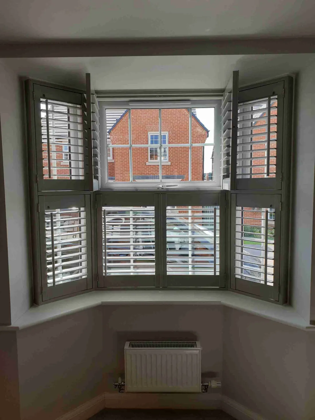 Angled bay with grey tier-on-tier shutters and the top tier opened