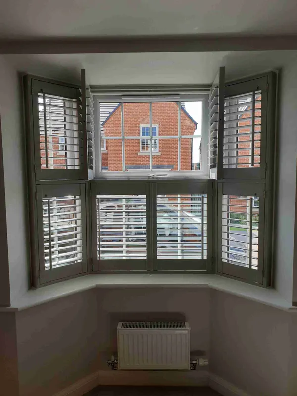 Angled bay with grey tier-on-tier shutters and the top tier opened