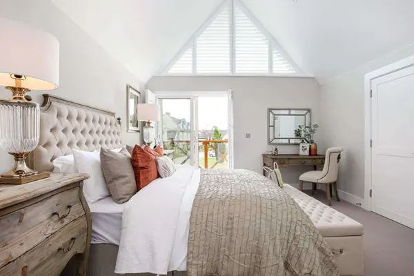 Bed below a gable window filled with shaped white shutters