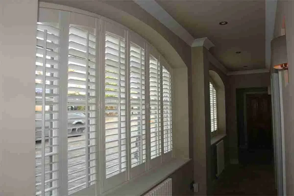 Hallway arched window with white shutters shaped to the curve