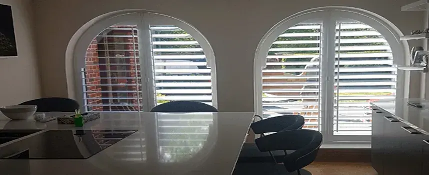 Kitchen diner with two arched windows and white shaped shutters