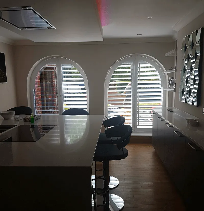 Modern kitchen with two arched windows fitted with white shutters