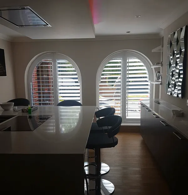 Modern kitchen with two arched windows fitted with white shutters