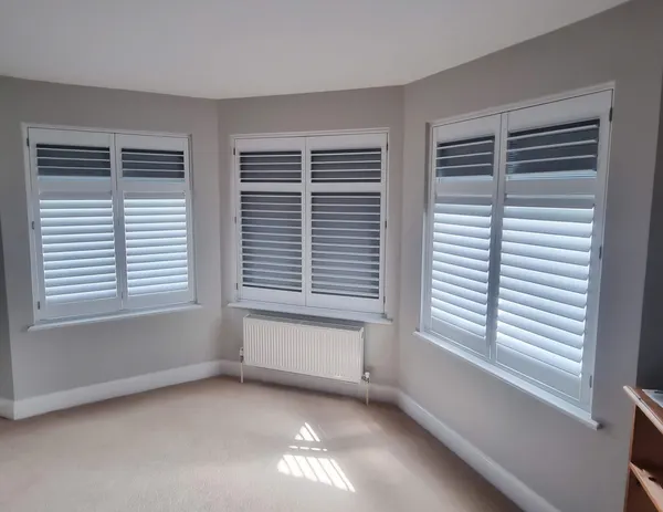 Bedroom bay with grey blackout shutters on each of its windows