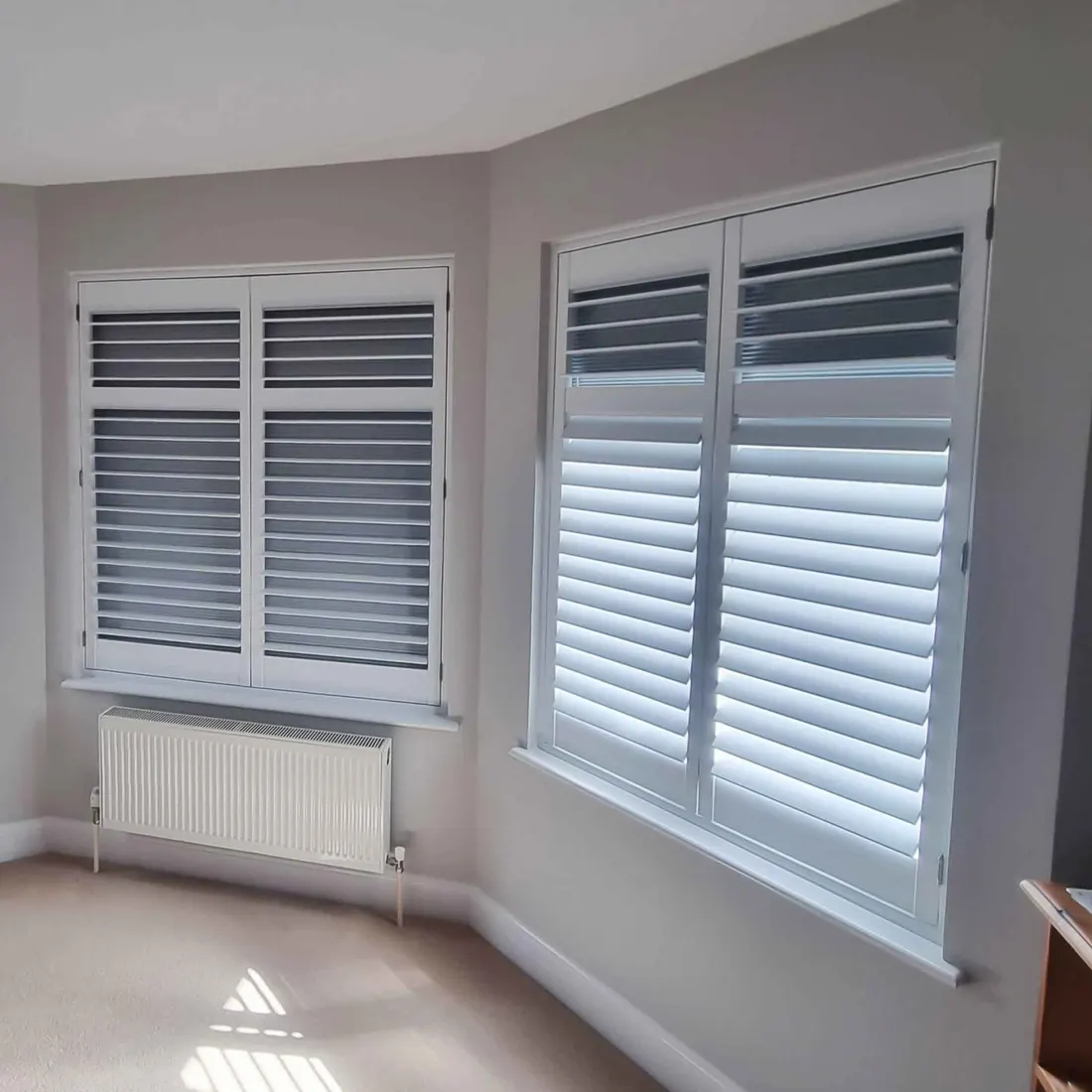 Two corner windows fitted with grey shutters and blackout blinds