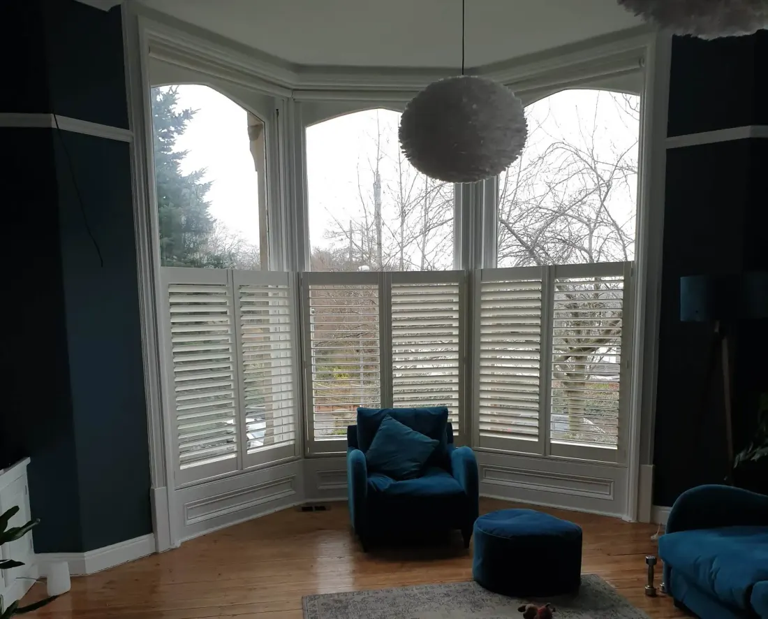 Blue walls and a blue armchair in a bay fitted with café style shutters