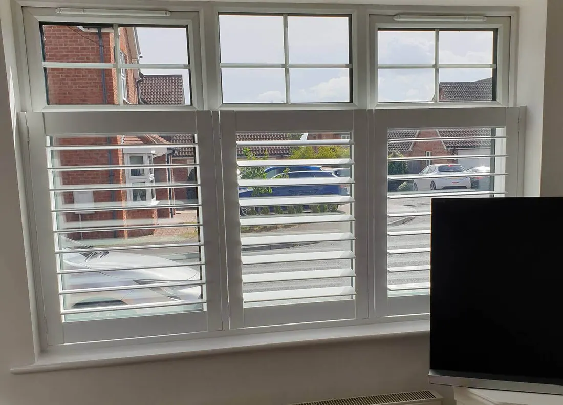 Front room window with small panes at the top and white café style shutters below