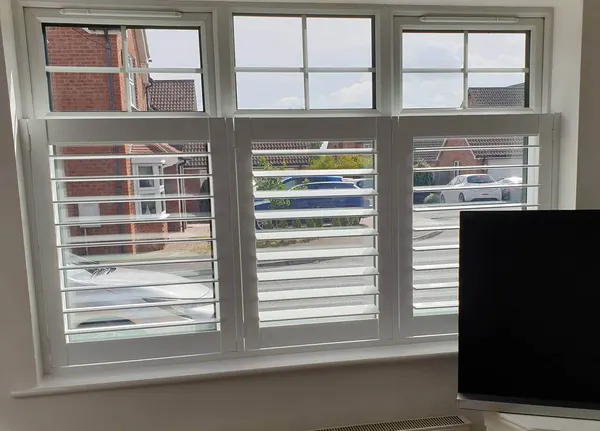 Front room window with small panes at the top and white café style shutters below