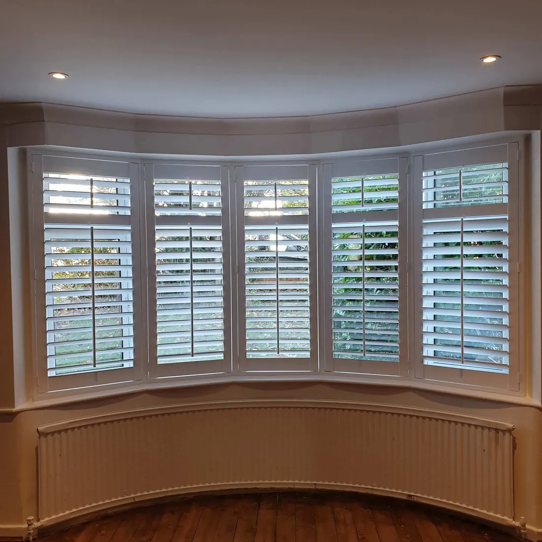 Dark walls round a curved bay fitted with white shutters