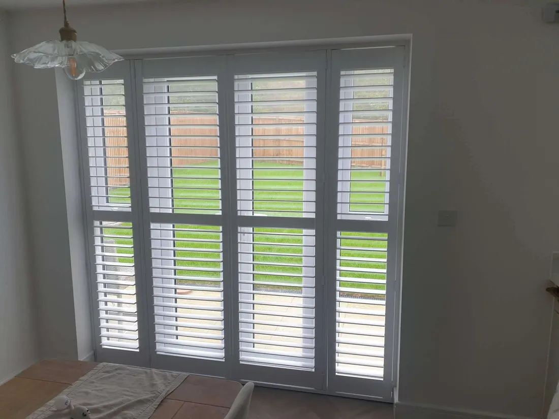 Tall glazed garden doors fitted with full height white shutters and a mid rail