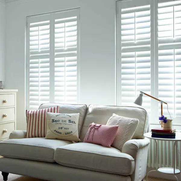 Cream sofa beside two tall windows with white full height shutters