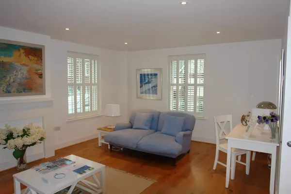Sitting room with a blue sofa in front of white full height shutters