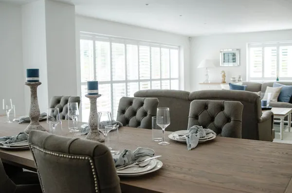Dining table laid for dinner in front of patio door shutters