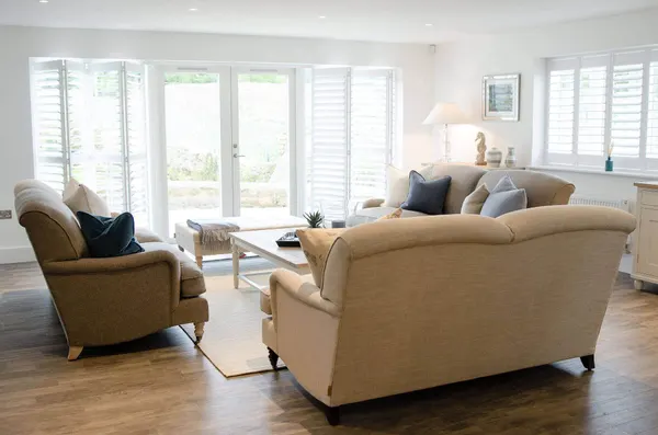 Two sofas facing wide patio doors fitted with shutters