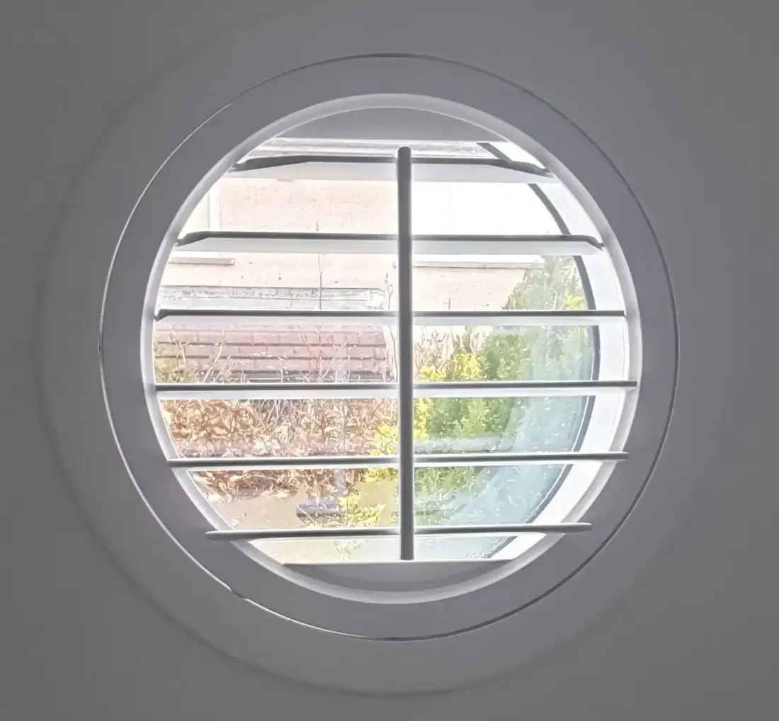 Round shutter with its split panels opened onto a garden