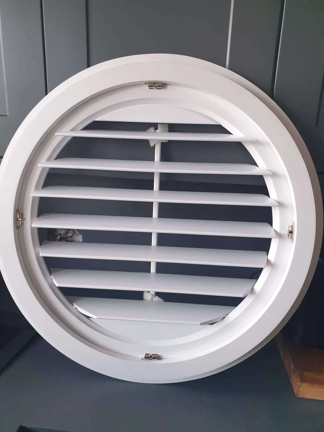 Close-up of a round white shutter with the louvres open