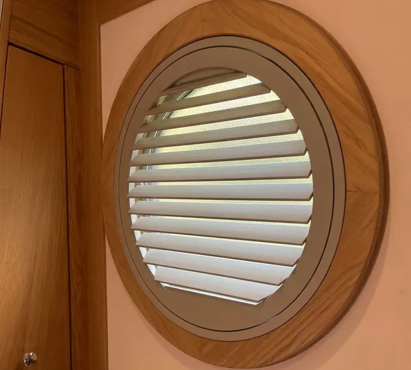 Timber porthole frame holding a round white shutter