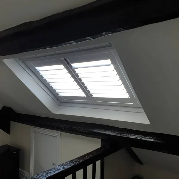 Loft landing with dark beams and white shutters on the skylight