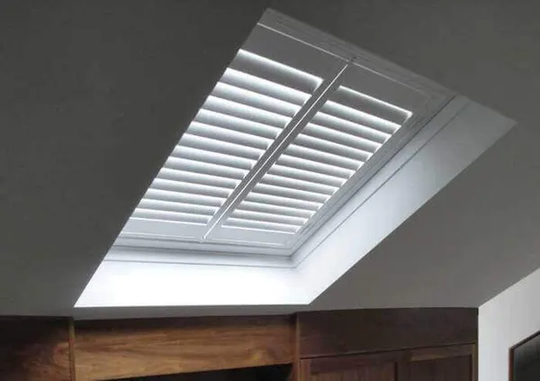 Daylight softened by angled white louvres on a skylight shutter