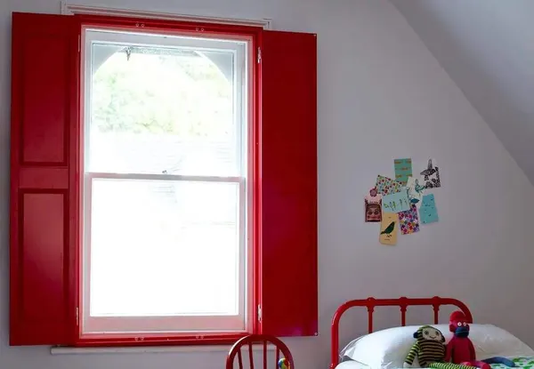 Child's bedroom sash window fitted with red solid panel shutters