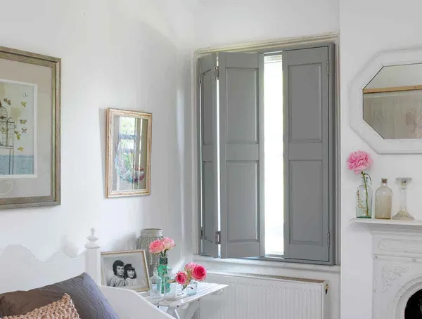 Bedroom window with grey solid raised panel shutters opened back