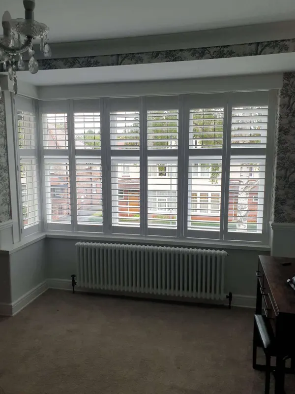 Front room square bay with white shutters on the front and both sides