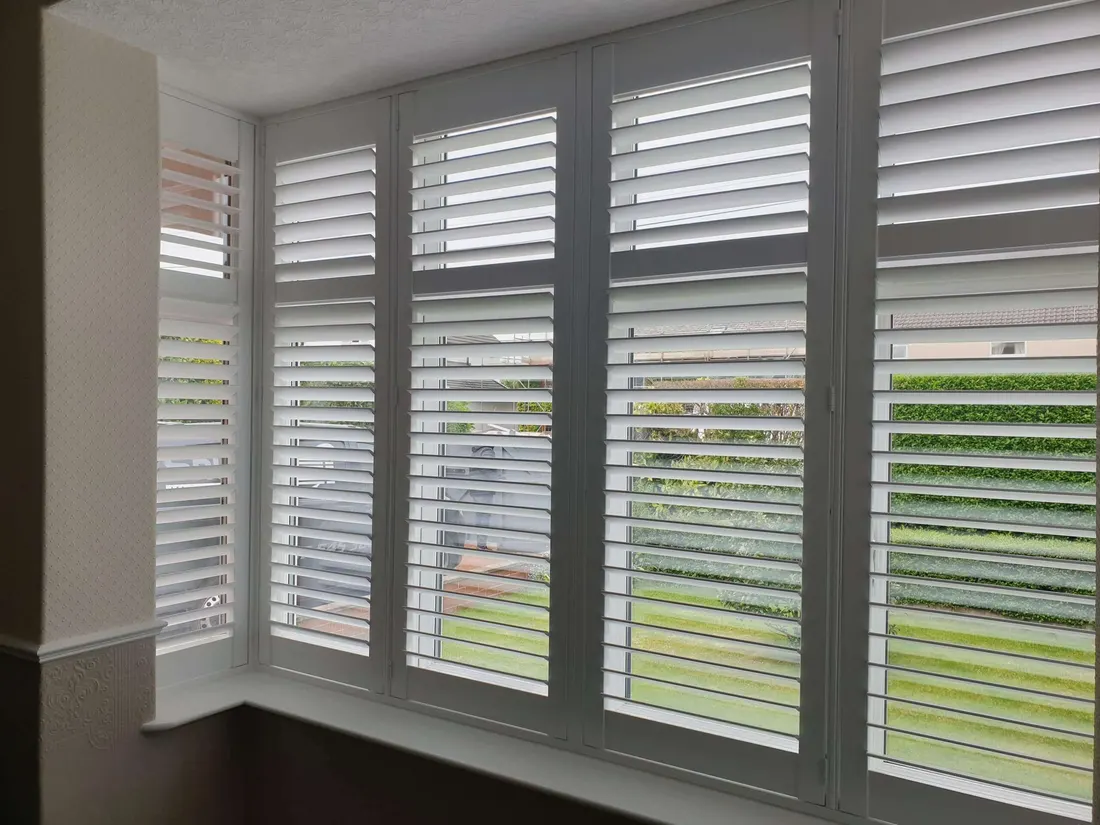 A square bay of white shutters, louvres tilted open to let the daylight in