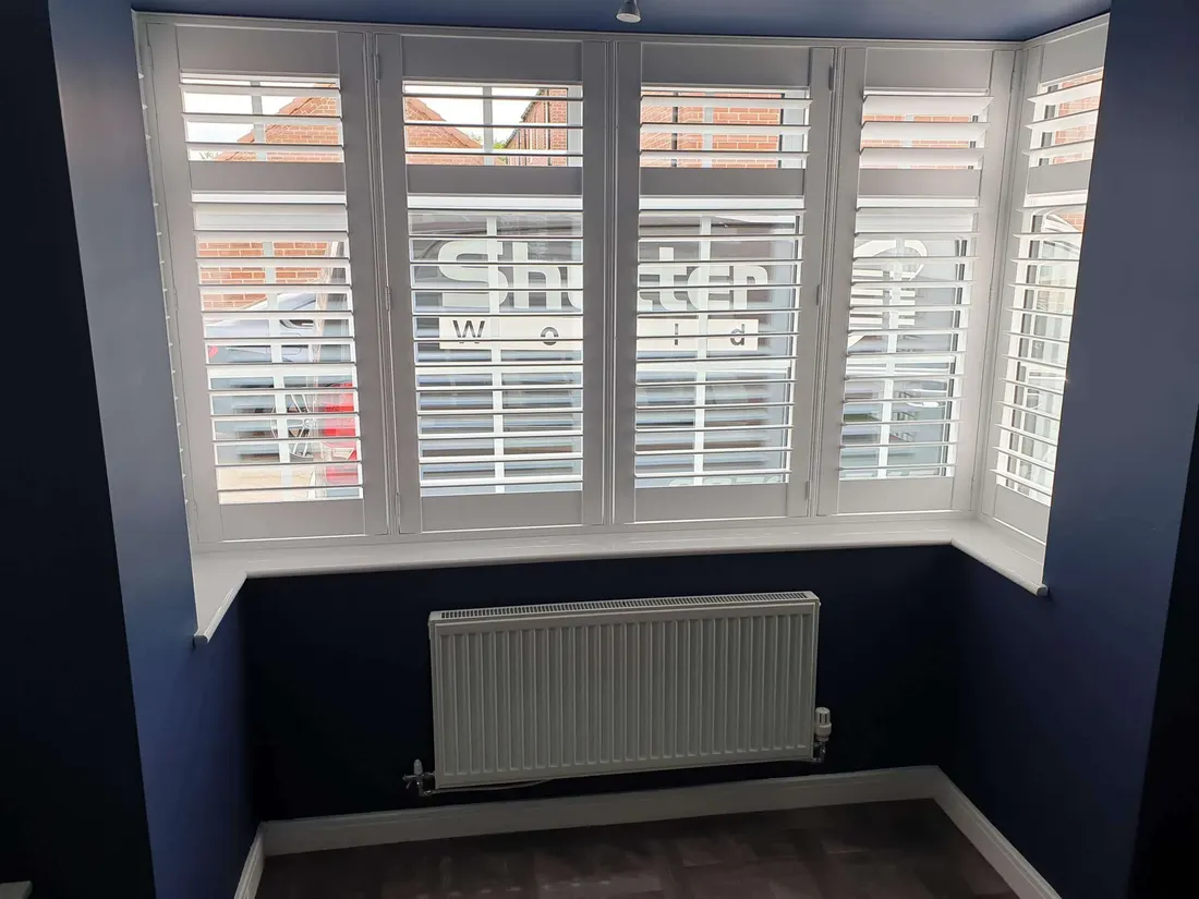 Navy blue walls round a square bay with white shutters over a radiator