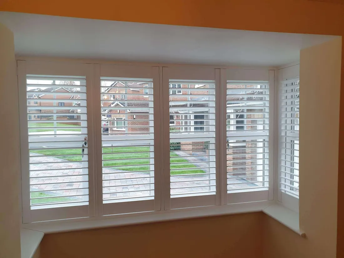 Orange wall beside a square bay window with white shutters
