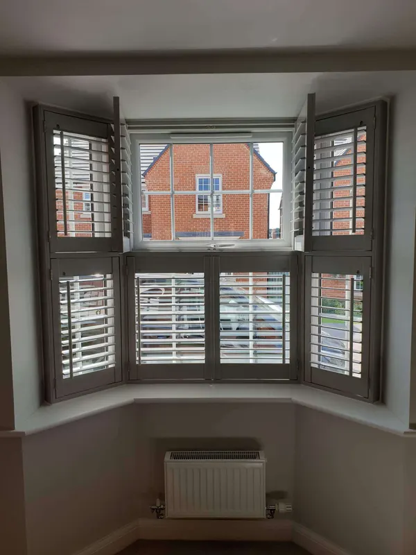 Bay window with grey tier-on-tier shutters, the upper tier folded back