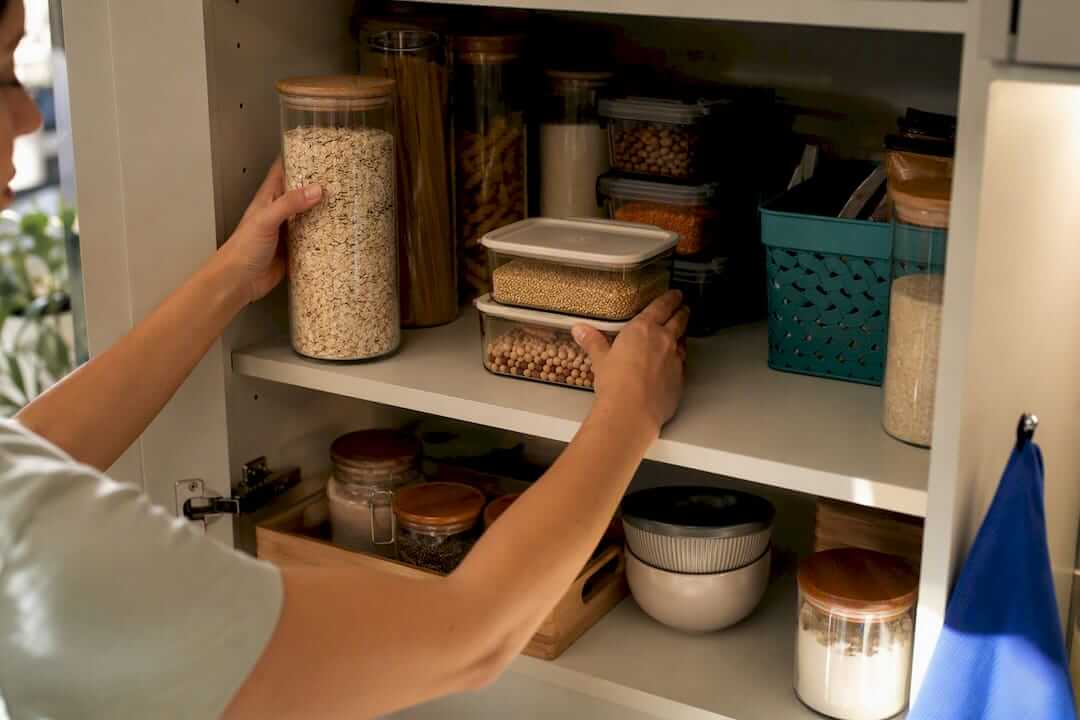 Hands organising a tidy kitchen cupboard
